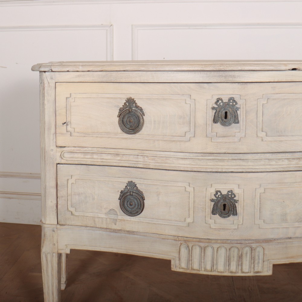 An off-white painted Italian serpentine front commode with two long drawers, panel moulding, metal handles, and square tapered legs. View II