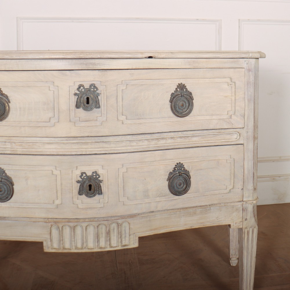 An off-white painted Italian serpentine front commode with two long drawers, panel moulding, metal handles, and square tapered legs. View V