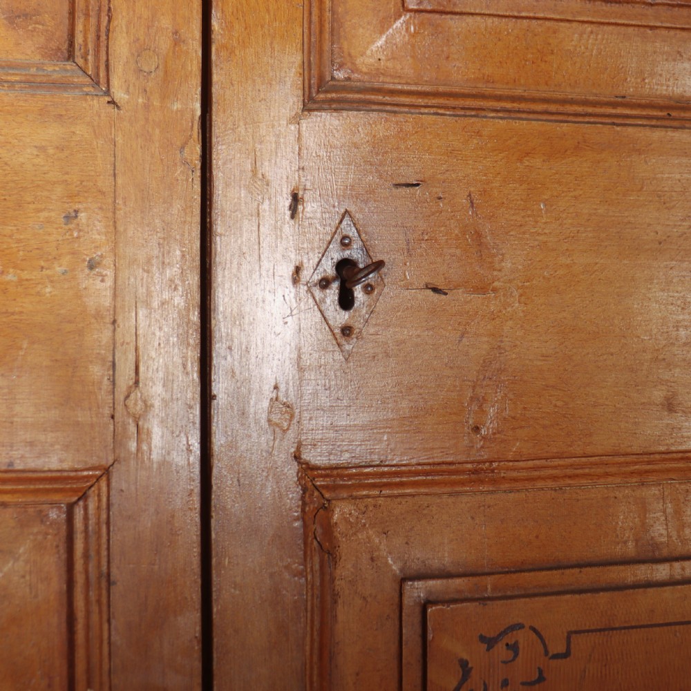 An antique freestanding pine linen cupboard featuring two panelled upper doors decorated with painted corner flourishes above two full-width lower drawers. View VII