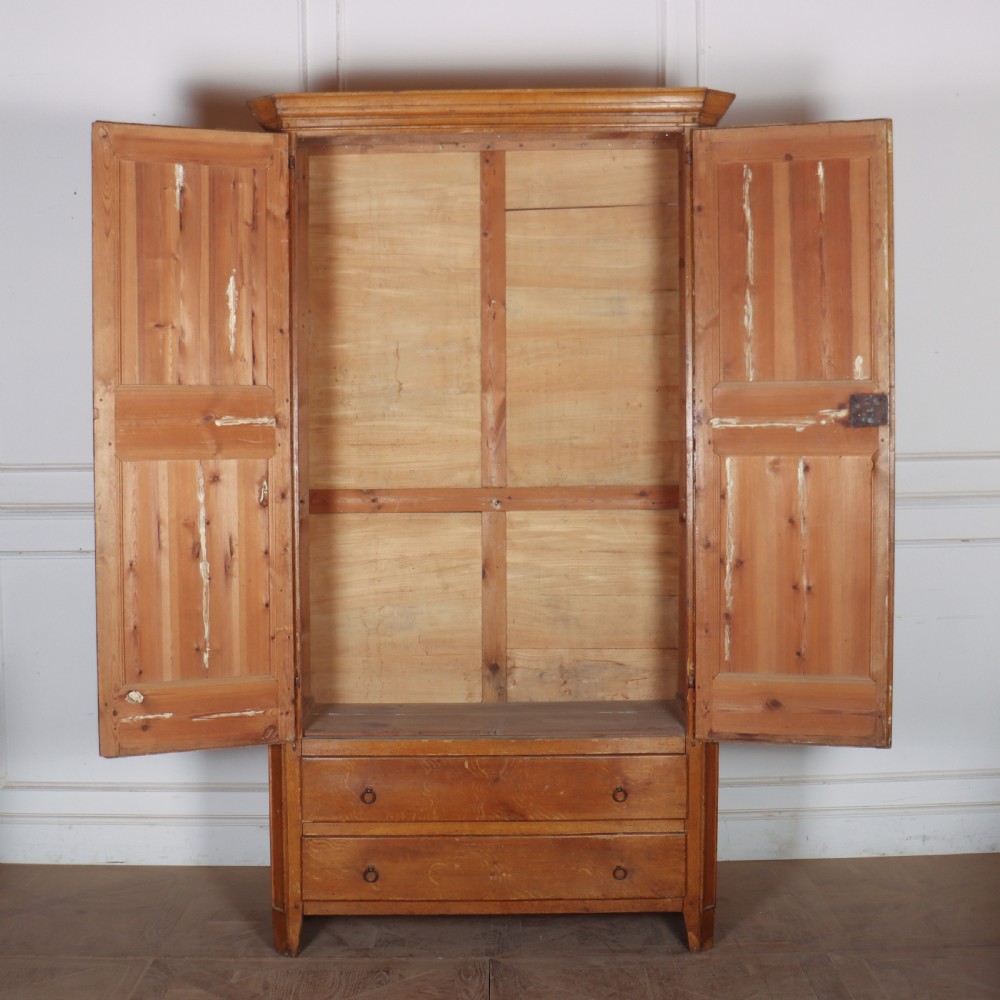 An antique freestanding pine linen cupboard featuring two panelled upper doors decorated with painted corner flourishes above two full-width lower drawers. View VIII