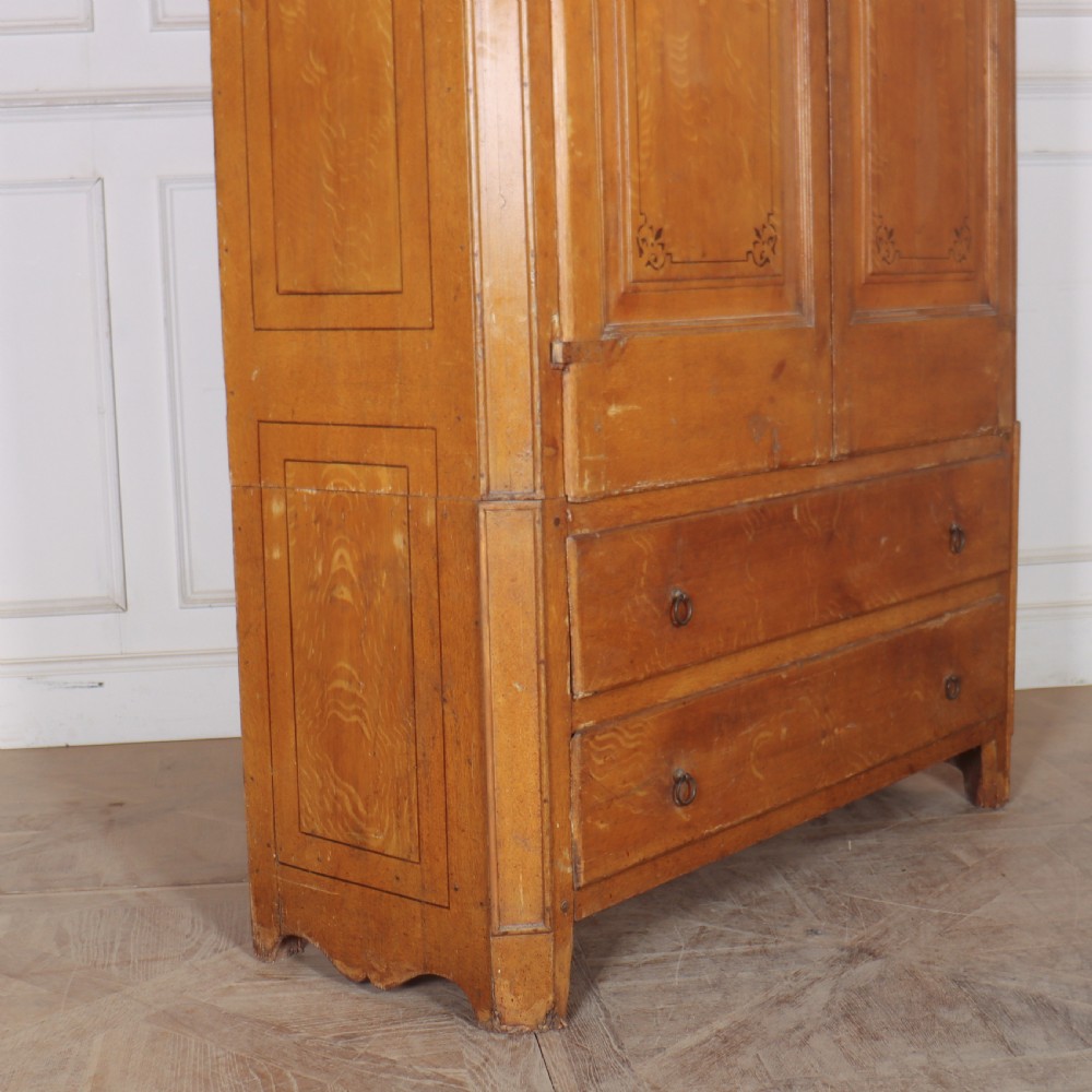 An antique freestanding pine linen cupboard featuring two panelled upper doors decorated with painted corner flourishes above two full-width lower drawers. View IX