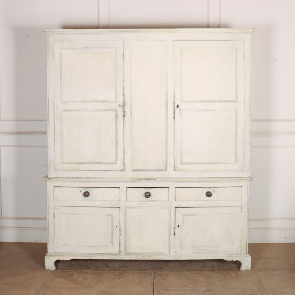 An 18th-century painted housekeepers cupboard featuring fielded panel upper doors, three central drawers, and lower storage cabinets on bracket feet.
