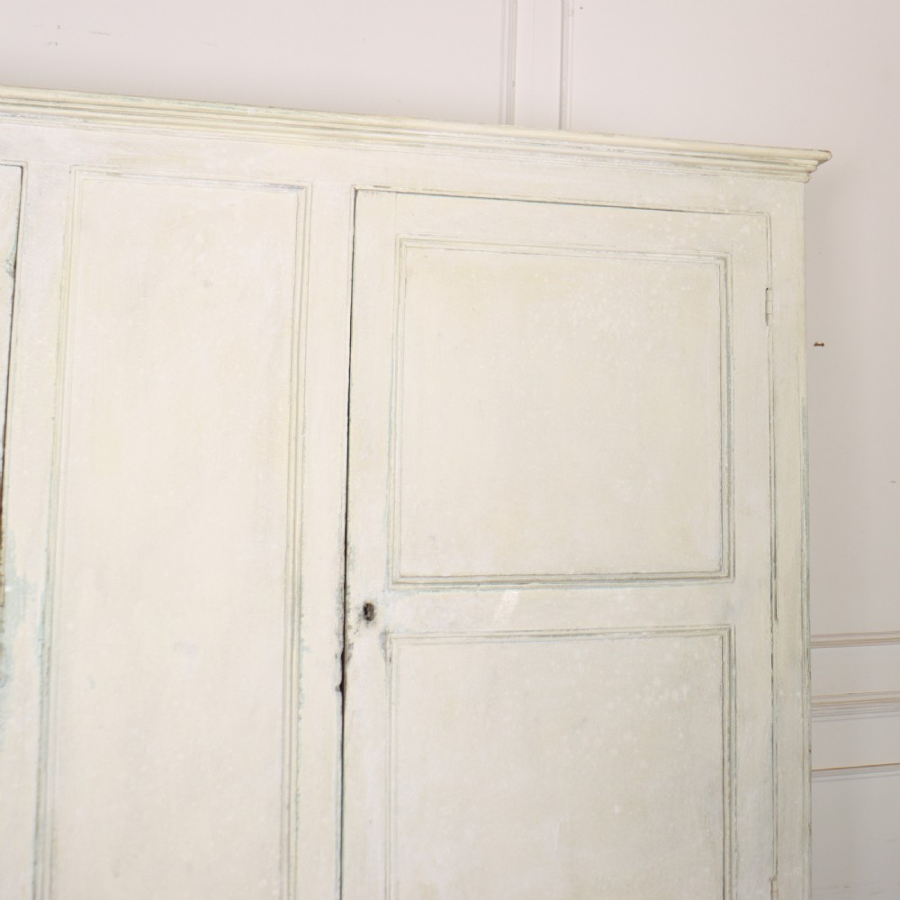 An 18th-century painted housekeepers cupboard featuring fielded panel upper doors, three central drawers, and lower storage cabinets on bracket feet. View VI