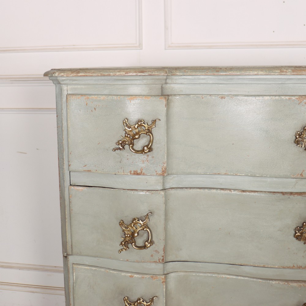 A four-drawer painted Danish serpentine front commode featuring ornate brass drop handles, keyhole escutcheons, and short cabriole legs. View II