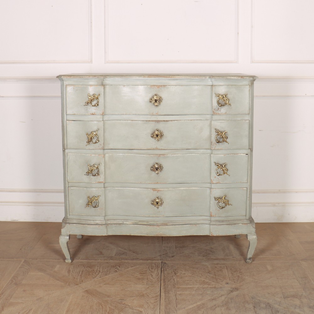 A four-drawer painted Danish serpentine front commode featuring ornate brass drop handles, keyhole escutcheons, and short cabriole legs.