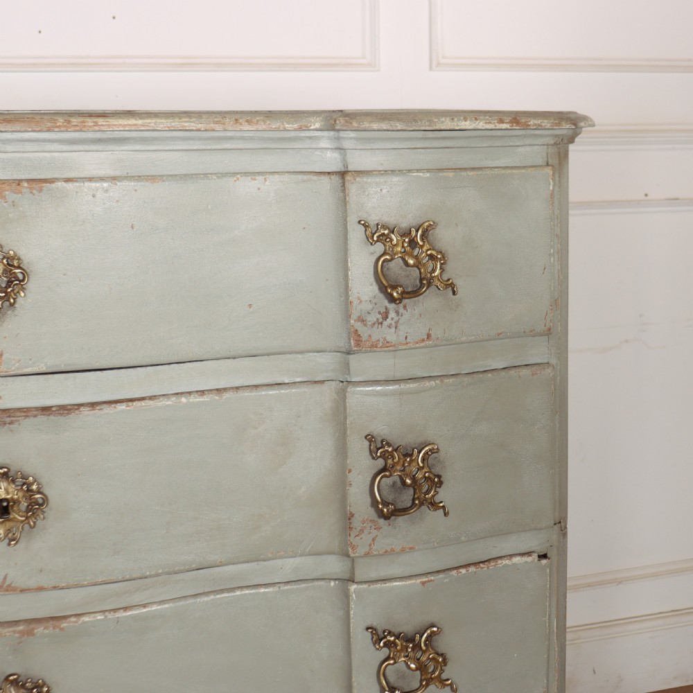 A four-drawer painted Danish serpentine front commode featuring ornate brass drop handles, keyhole escutcheons, and short cabriole legs. View III