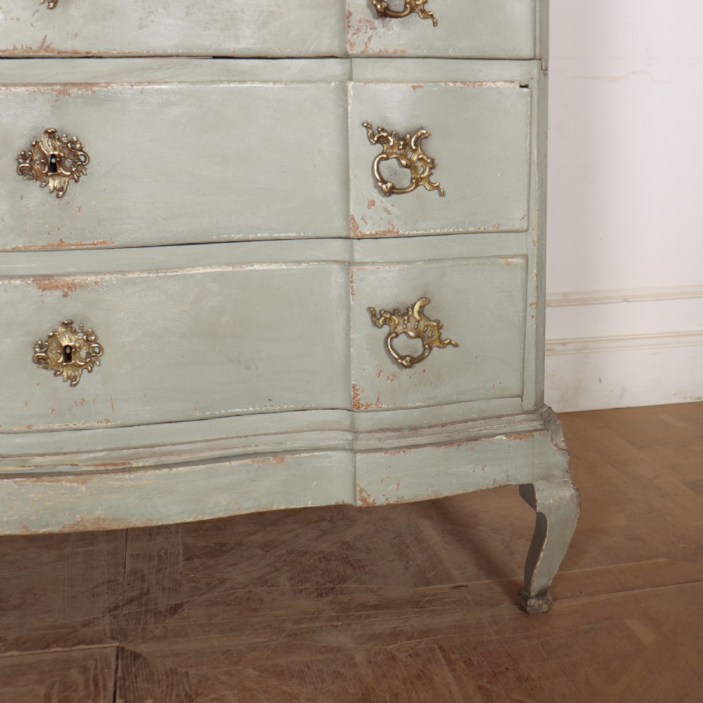 A four-drawer painted Danish serpentine front commode featuring ornate brass drop handles, keyhole escutcheons, and short cabriole legs. View V