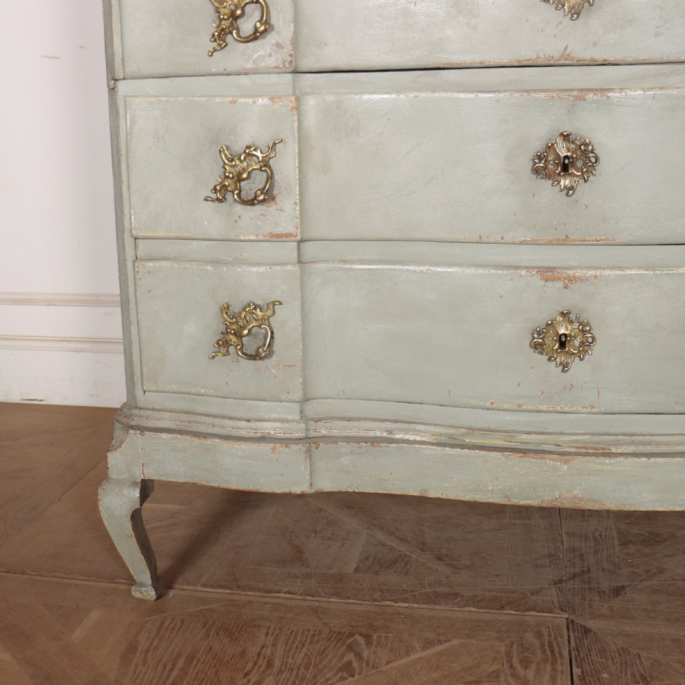 A four-drawer painted Danish serpentine front commode featuring ornate brass drop handles, keyhole escutcheons, and short cabriole legs. View VI