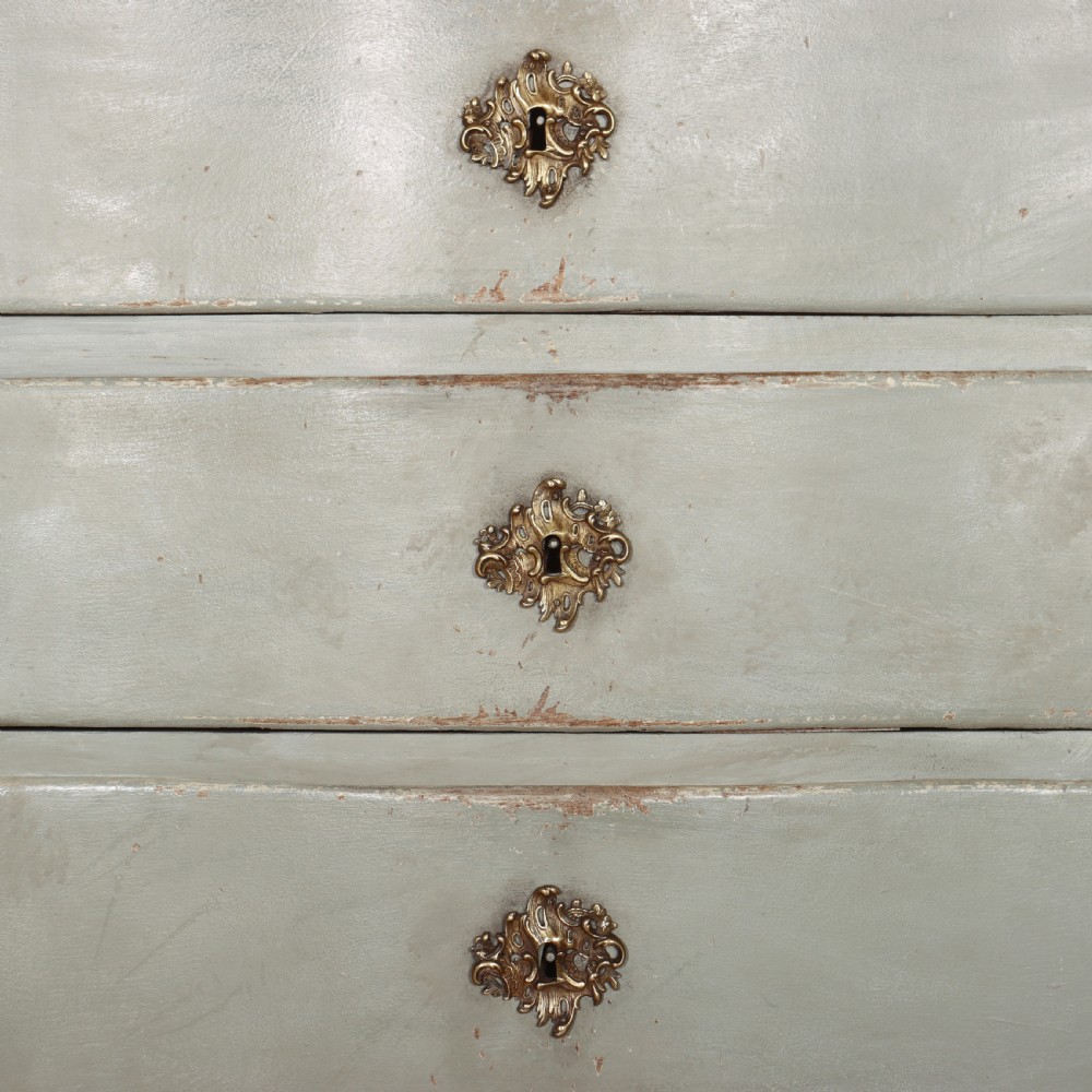 A four-drawer painted Danish serpentine front commode featuring ornate brass drop handles, keyhole escutcheons, and short cabriole legs. View VII