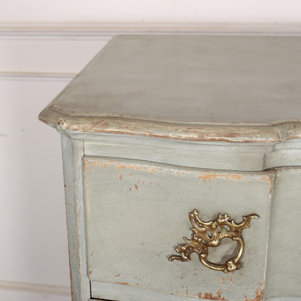 A four-drawer painted Danish serpentine front commode featuring ornate brass drop handles, keyhole escutcheons, and short cabriole legs. View VIII