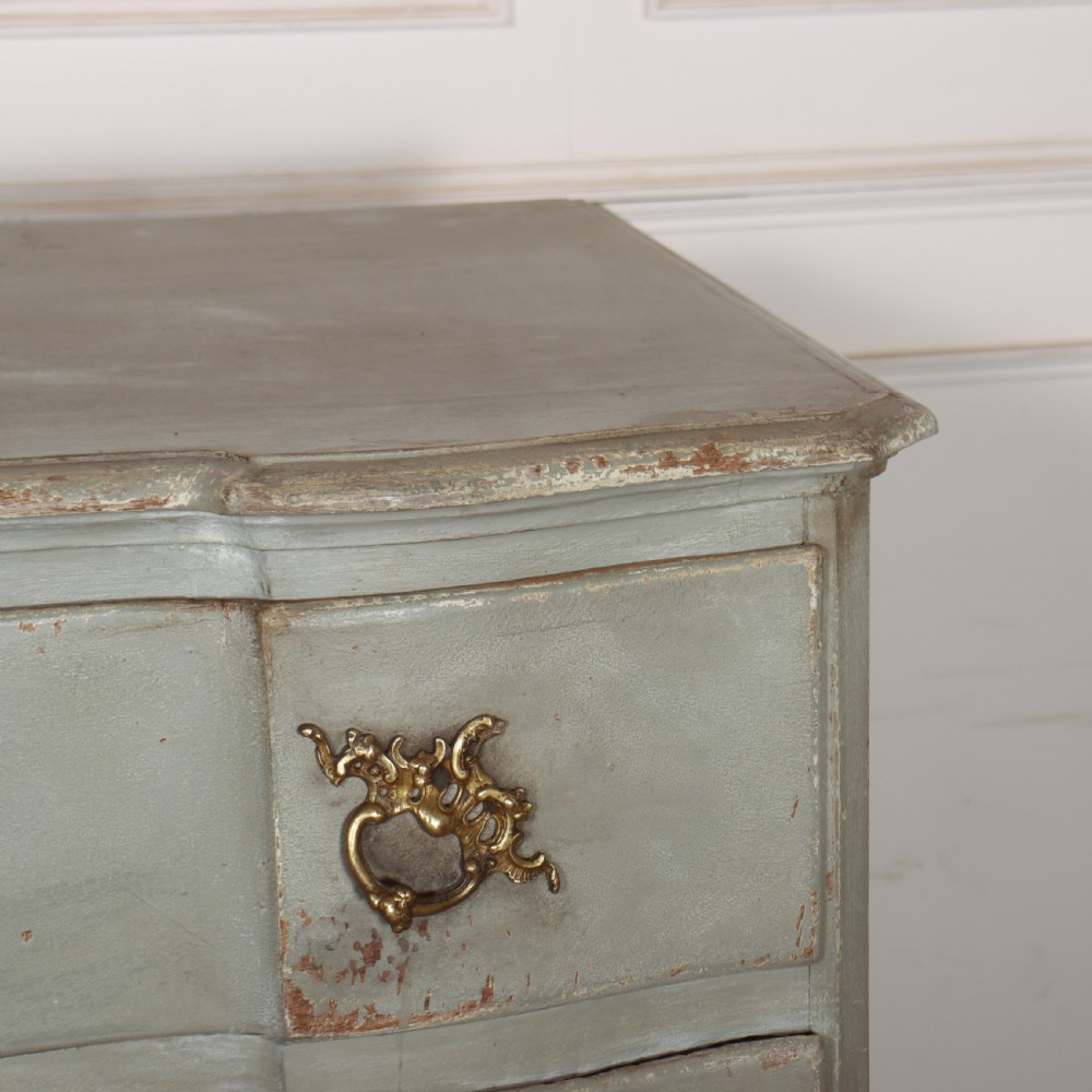 A four-drawer painted Danish serpentine front commode featuring ornate brass drop handles, keyhole escutcheons, and short cabriole legs. View IX