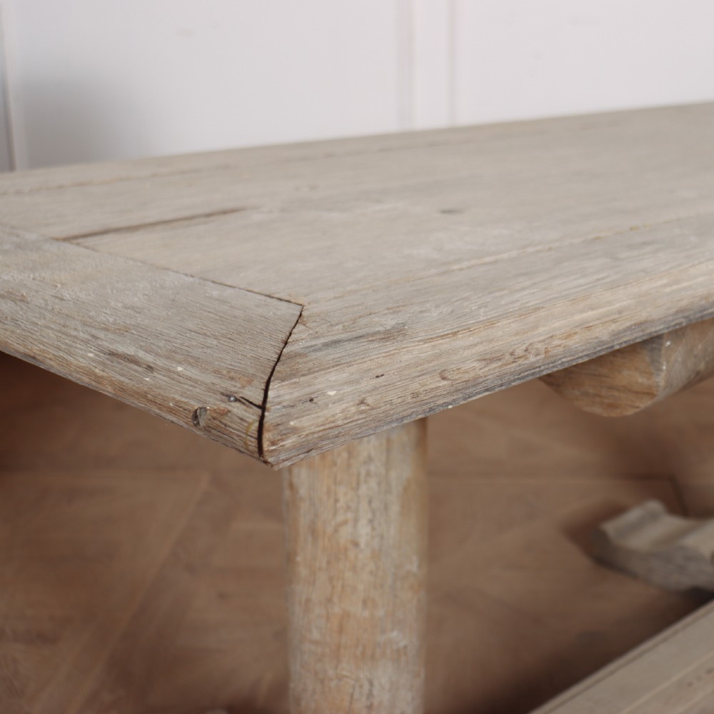 A long rectangular bleached oak trestle table featuring three column support legs and scrolled feet. View III