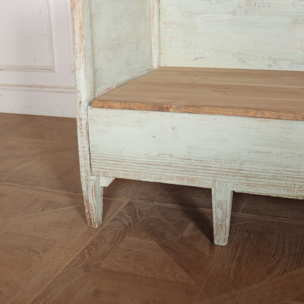 A pale green painted Swedish wooden bench featuring a shaped crest rail, panelled sides, and a natural pine seat. View III