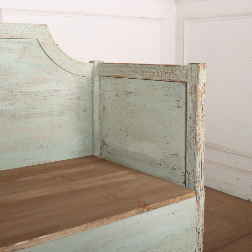 A pale green painted Swedish wooden bench featuring a shaped crest rail, panelled sides, and a natural pine seat. View V