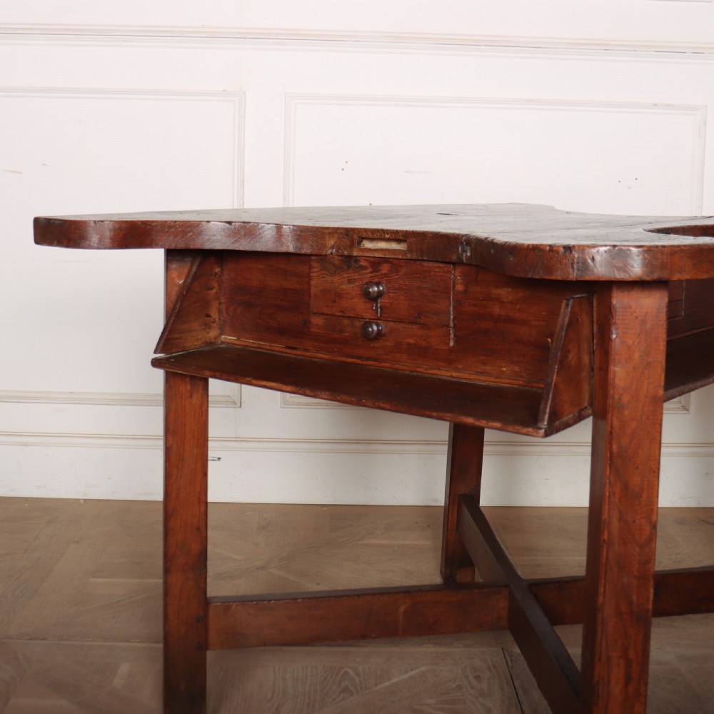 A nineteenth-century French wooden watchmakers table featuring a contoured ergonomic front cut-out, small drawers, and cross-braced square legs. View II
