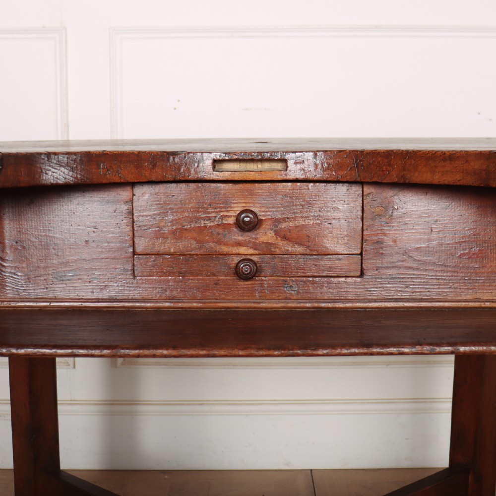 A nineteenth-century French wooden watchmakers table featuring a contoured ergonomic front cut-out, small drawers, and cross-braced square legs. View IV