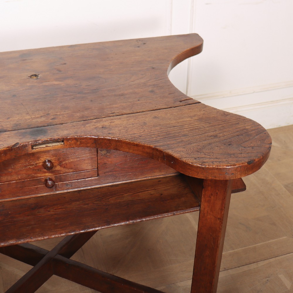 A nineteenth-century French wooden watchmakers table featuring a contoured ergonomic front cut-out, small drawers, and cross-braced square legs. View V