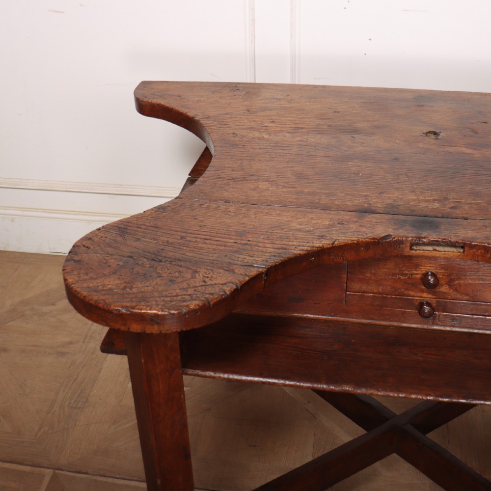 A nineteenth-century French wooden watchmakers table featuring a contoured ergonomic front cut-out, small drawers, and cross-braced square legs. View VI