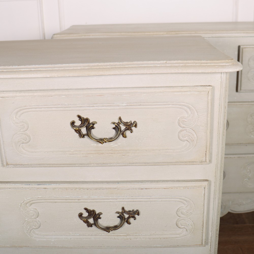 A pair of light cream painted French commodes featuring three drawers each, detailed with brass handles, carved apron shells, and cabriole legs. View III