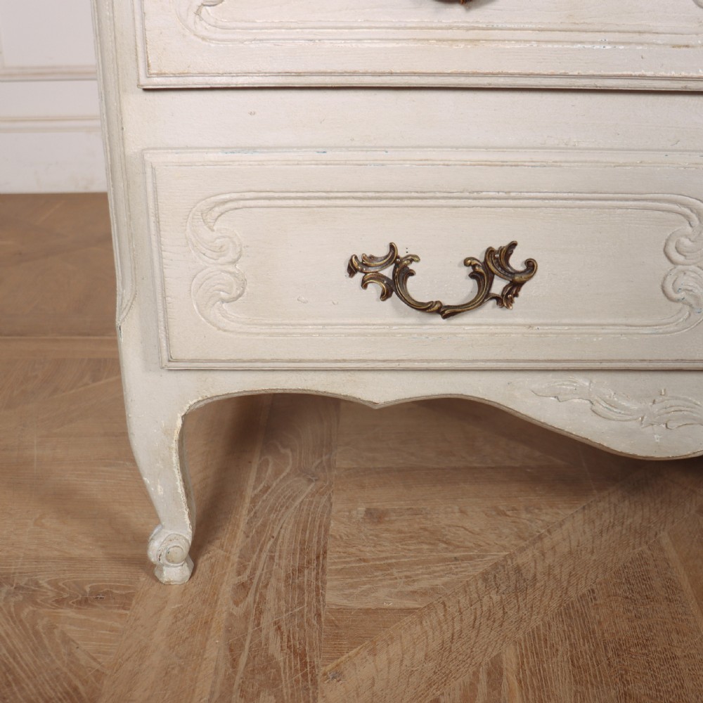 A pair of light cream painted French commodes featuring three drawers each, detailed with brass handles, carved apron shells, and cabriole legs. View IV