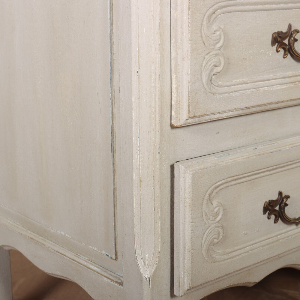 A pair of light cream painted French commodes featuring three drawers each, detailed with brass handles, carved apron shells, and cabriole legs. View XII