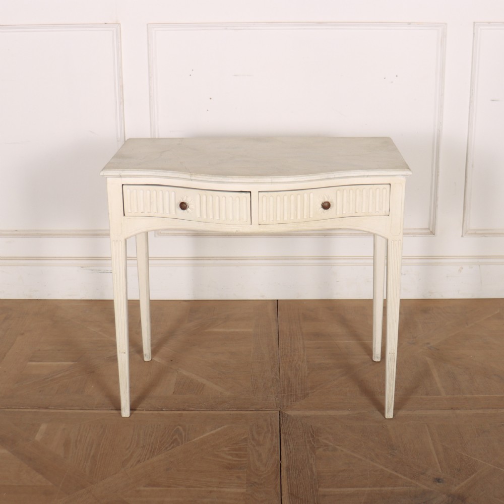 An off-white painted French side table with a serpentine front, fluted double drawer panels, and tapered square legs.