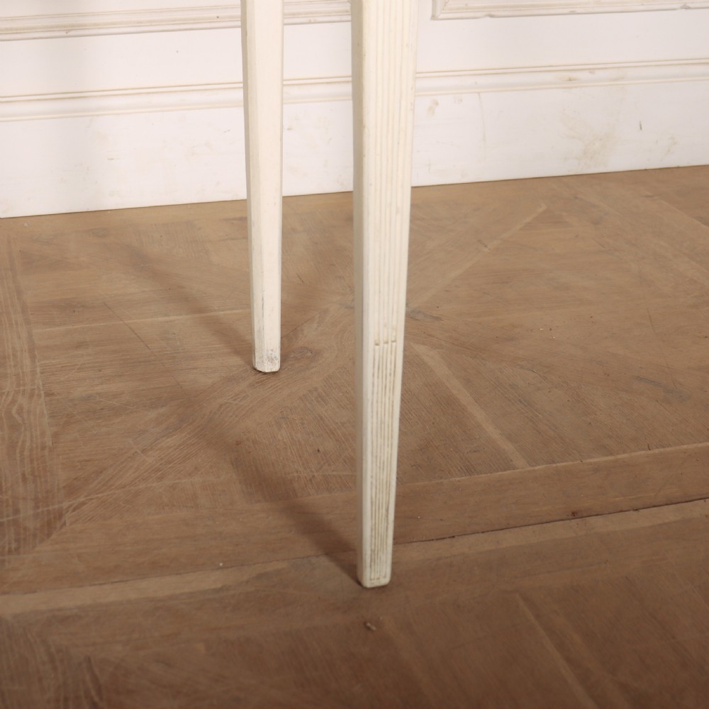 An off-white painted French side table with a serpentine front, fluted double drawer panels, and tapered square legs. View II