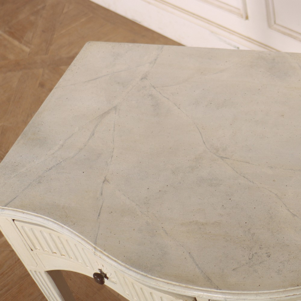An off-white painted French side table with a serpentine front, fluted double drawer panels, and tapered square legs. View XI