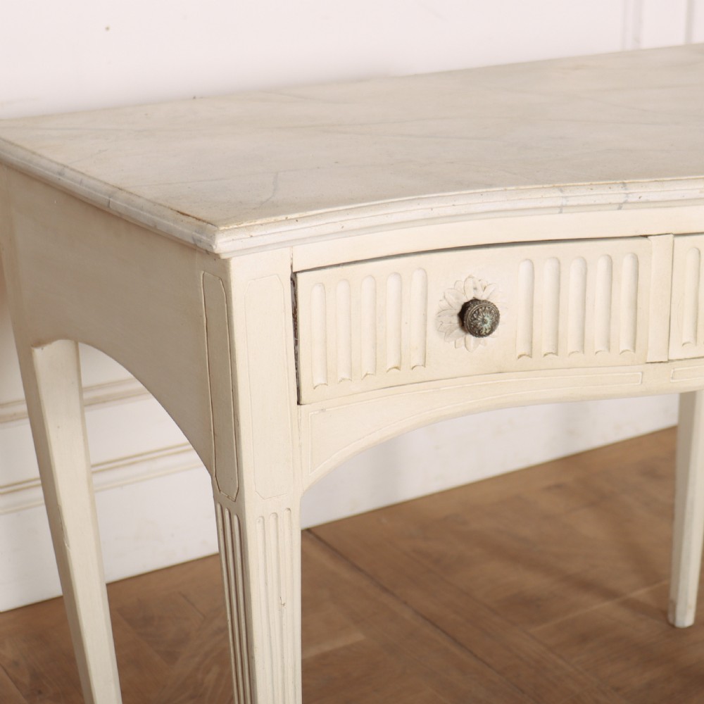 A 19th-century French off-white painted side table featuring a gentle curved front, three fluted drawers, tapered legs, and a marble top. View II