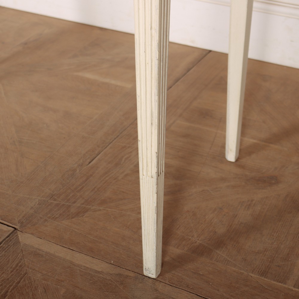 A 19th-century French off-white painted side table featuring a gentle curved front, three fluted drawers, tapered legs, and a marble top. View IV