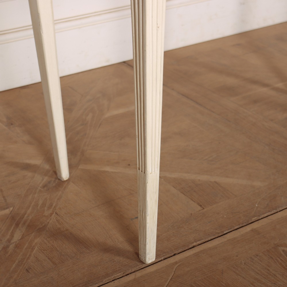 A 19th-century French off-white painted side table featuring a gentle curved front, three fluted drawers, tapered legs, and a marble top. View V