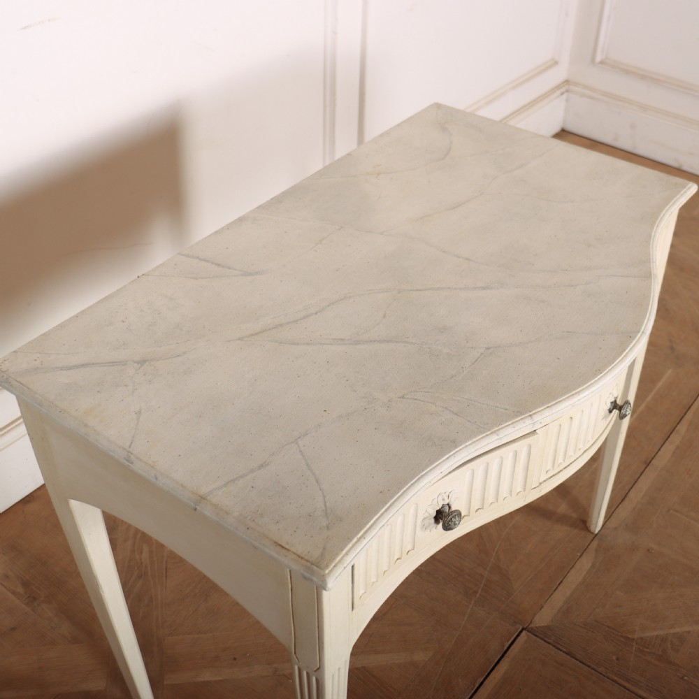 A 19th-century French off-white painted side table featuring a gentle curved front, three fluted drawers, tapered legs, and a marble top. View VI