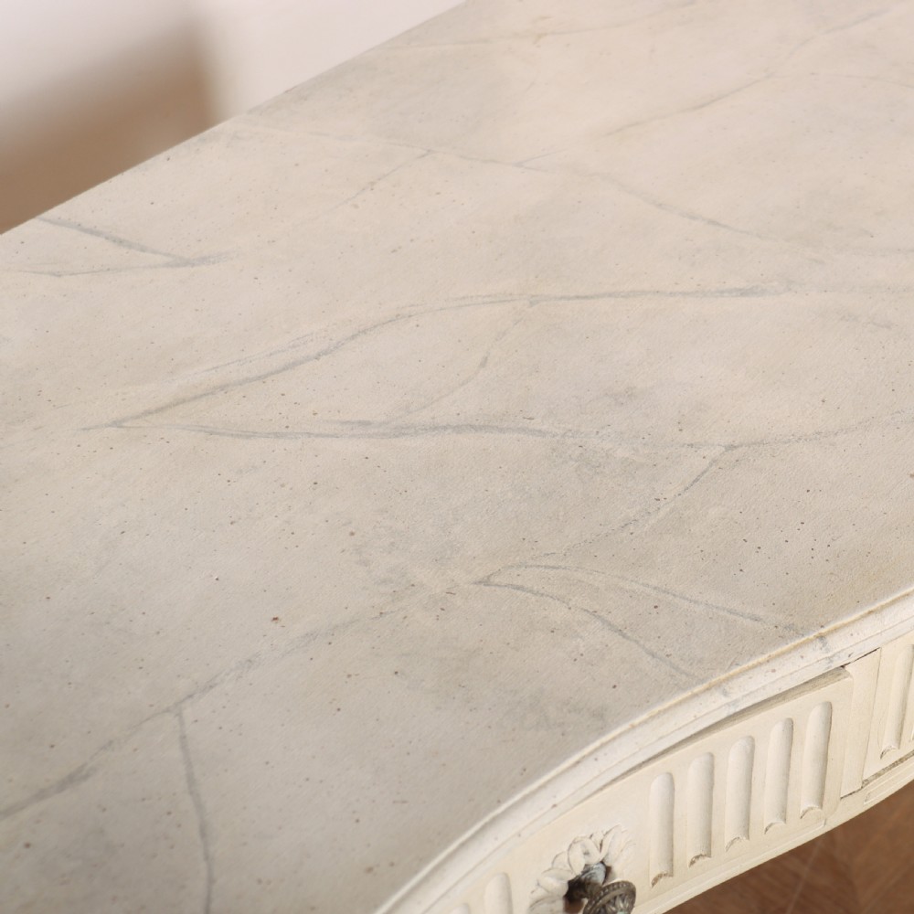 A 19th-century French off-white painted side table featuring a gentle curved front, three fluted drawers, tapered legs, and a marble top. View VIII