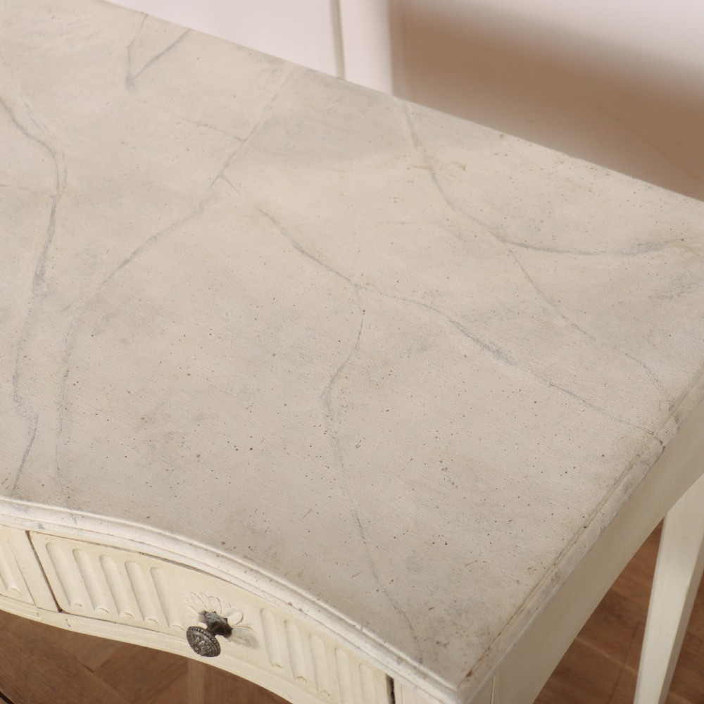A 19th-century French off-white painted side table featuring a gentle curved front, three fluted drawers, tapered legs, and a marble top. View IX