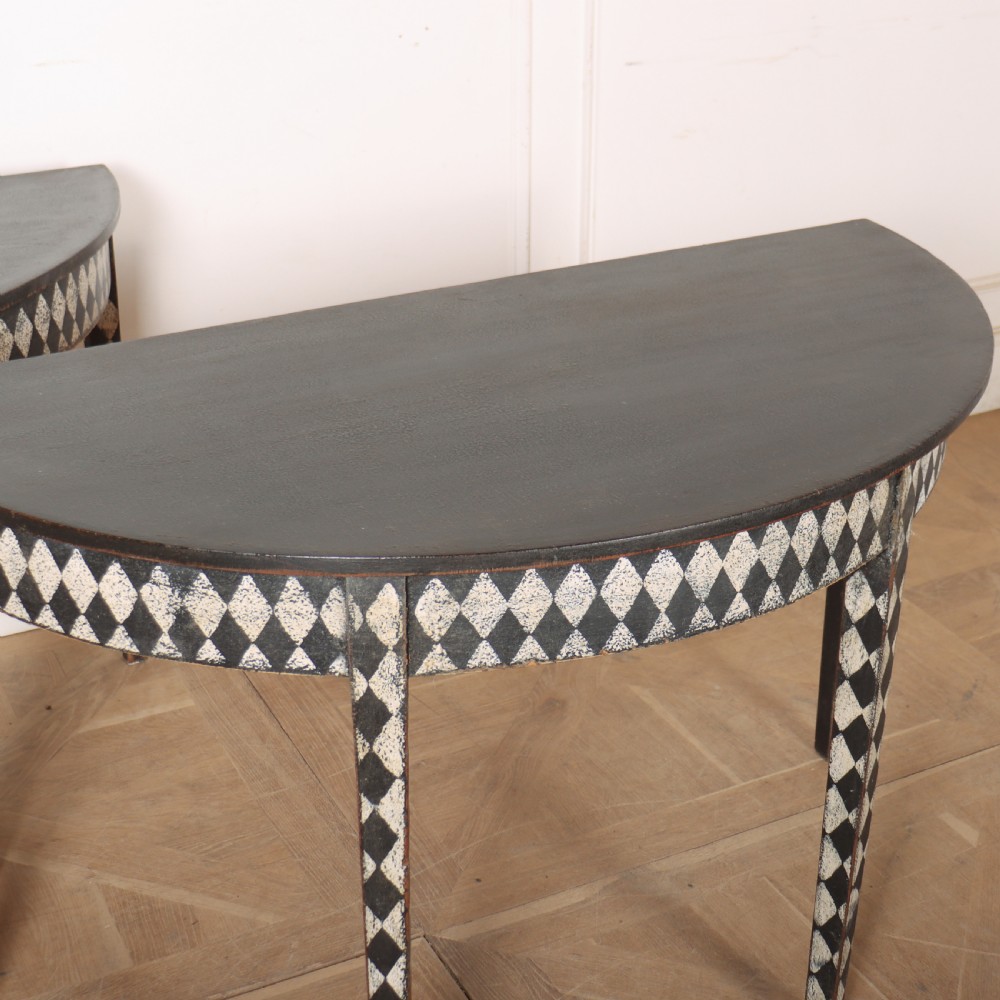 A pair of semi-circular painted timber console tables decorated with a black and white diamond harlequin pattern along the aprons and tapered legs. View VIII