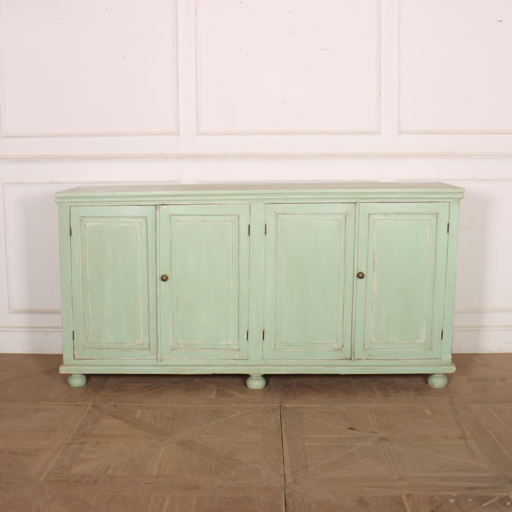 A large four-door wooden buffet painted in a soft pale green finish with simple panelled doors and turned feet.