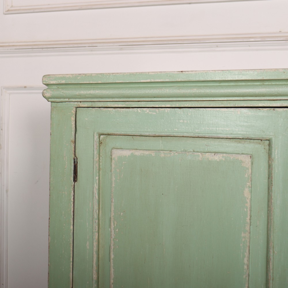 A large four-door wooden buffet painted in a soft pale green finish with simple panelled doors and turned feet. View II