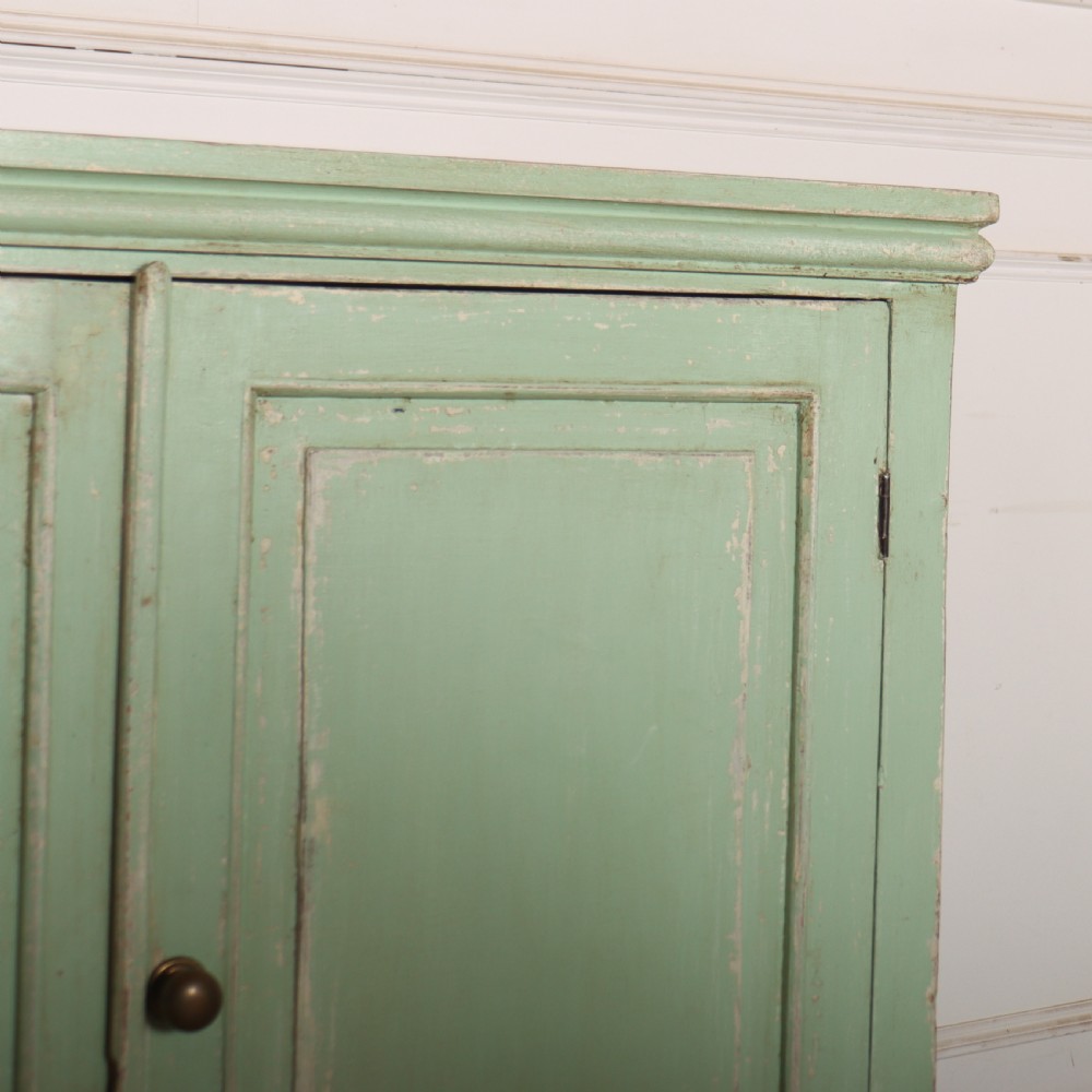 A large four-door wooden buffet painted in a soft pale green finish with simple panelled doors and turned feet. View III