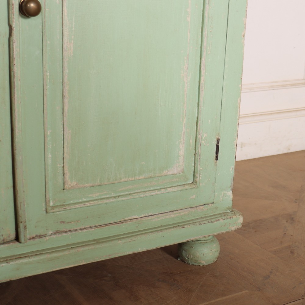 A large four-door wooden buffet painted in a soft pale green finish with simple panelled doors and turned feet. View V