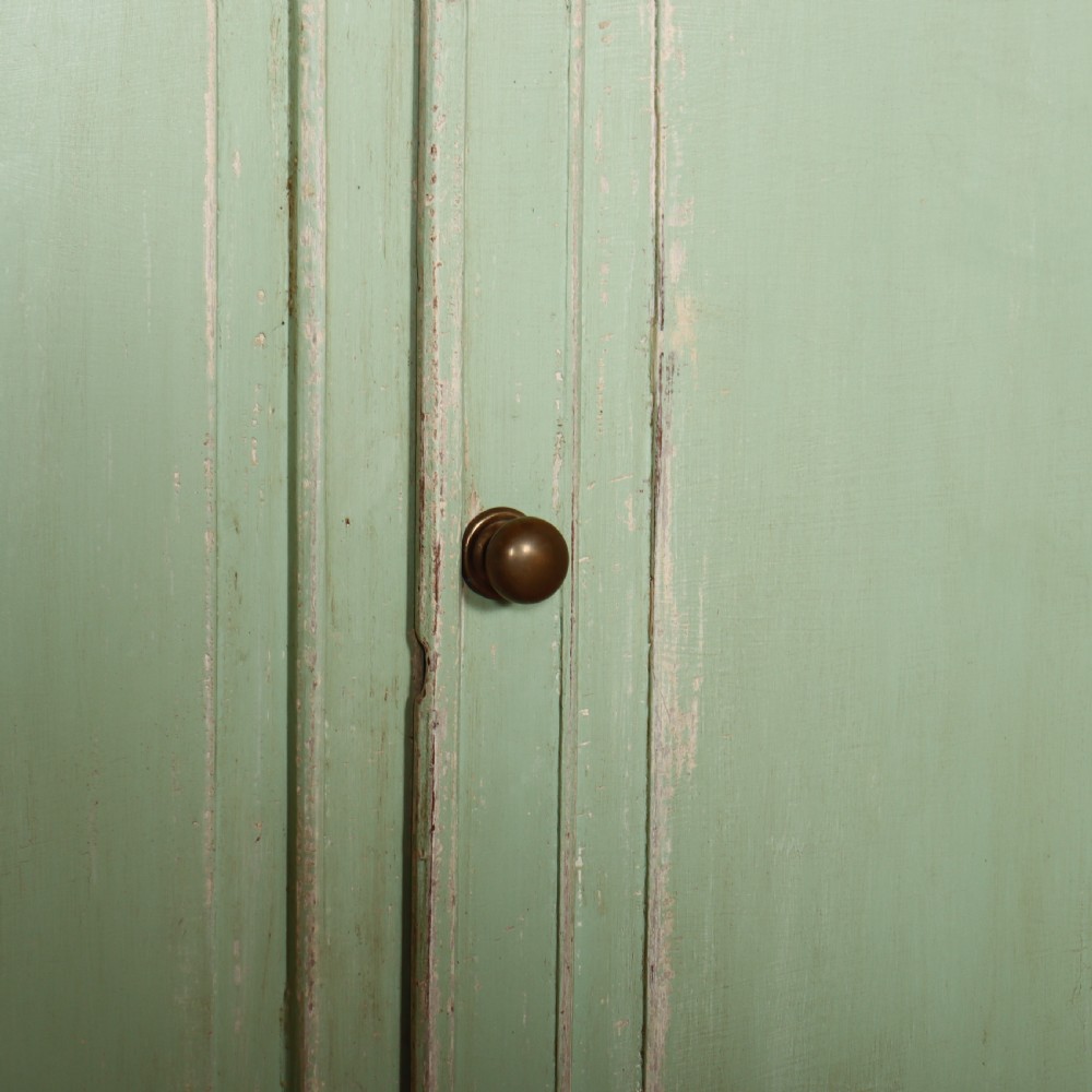 A large four-door wooden buffet painted in a soft pale green finish with simple panelled doors and turned feet. View VII
