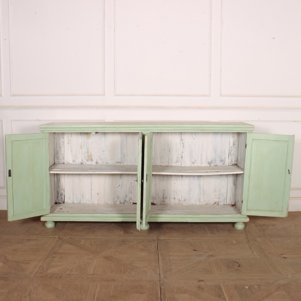 A large four-door wooden buffet painted in a soft pale green finish with simple panelled doors and turned feet. View VIII
