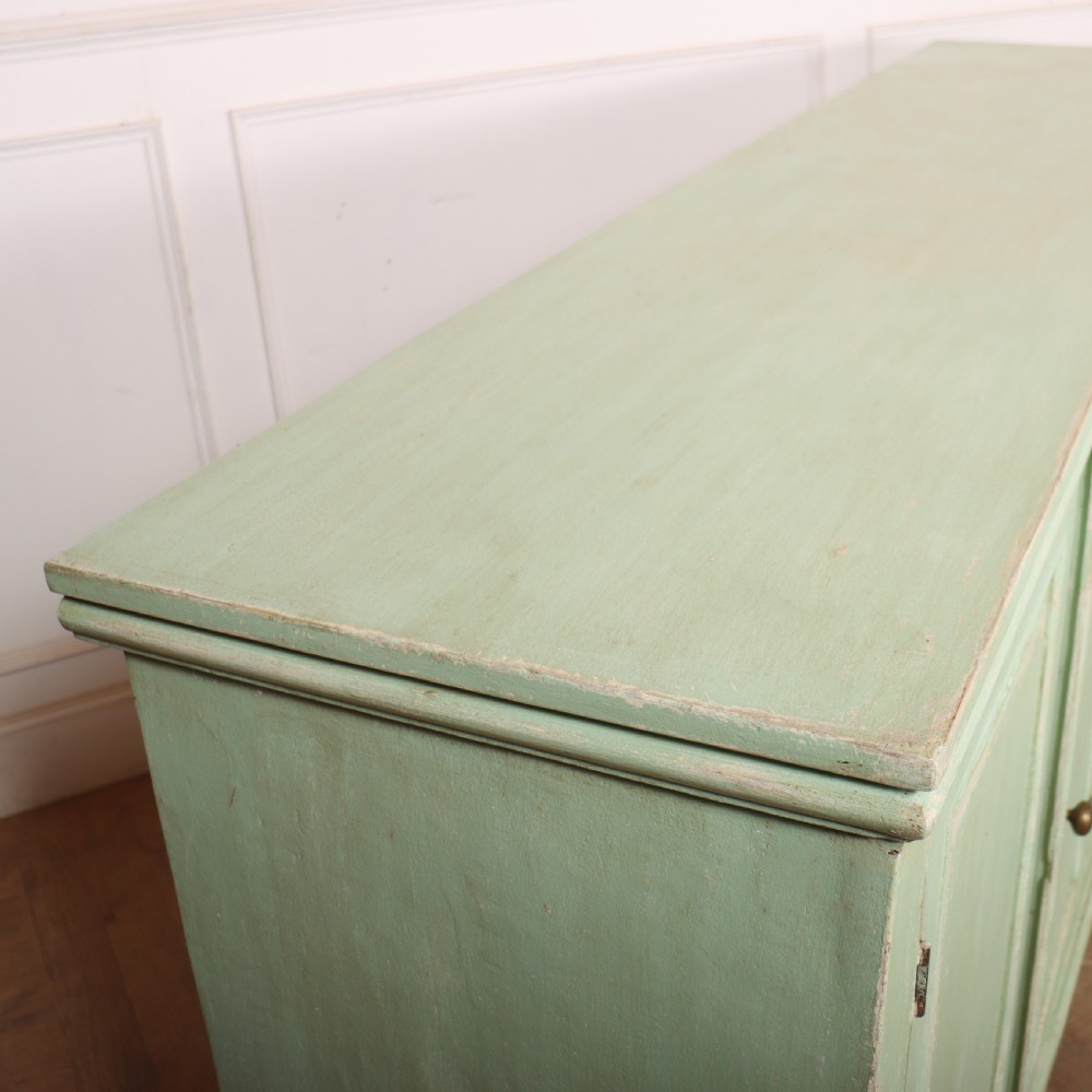 A large four-door wooden buffet painted in a soft pale green finish with simple panelled doors and turned feet. View XI