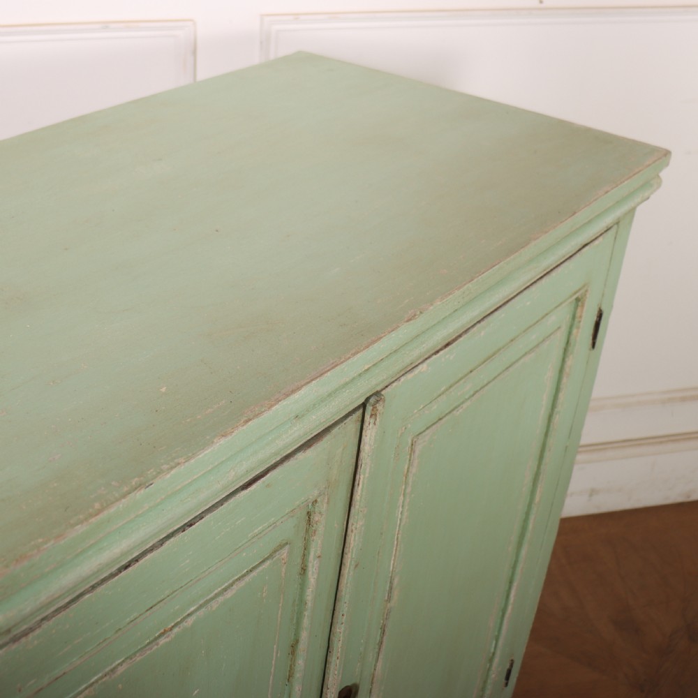 A large four-door wooden buffet painted in a soft pale green finish with simple panelled doors and turned feet. View XII