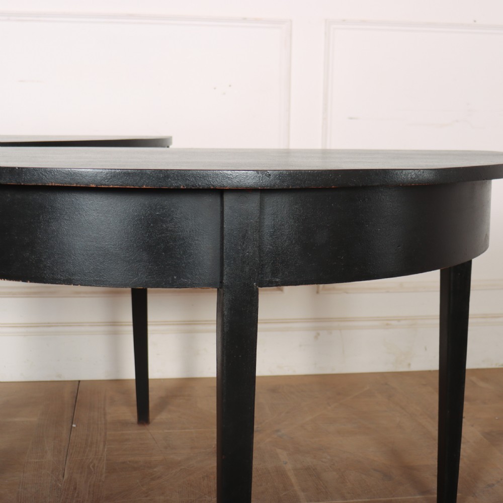 A pair of semi-circular ebonised wooden demi-lune console tables with plain aprons and square tapered legs. View II
