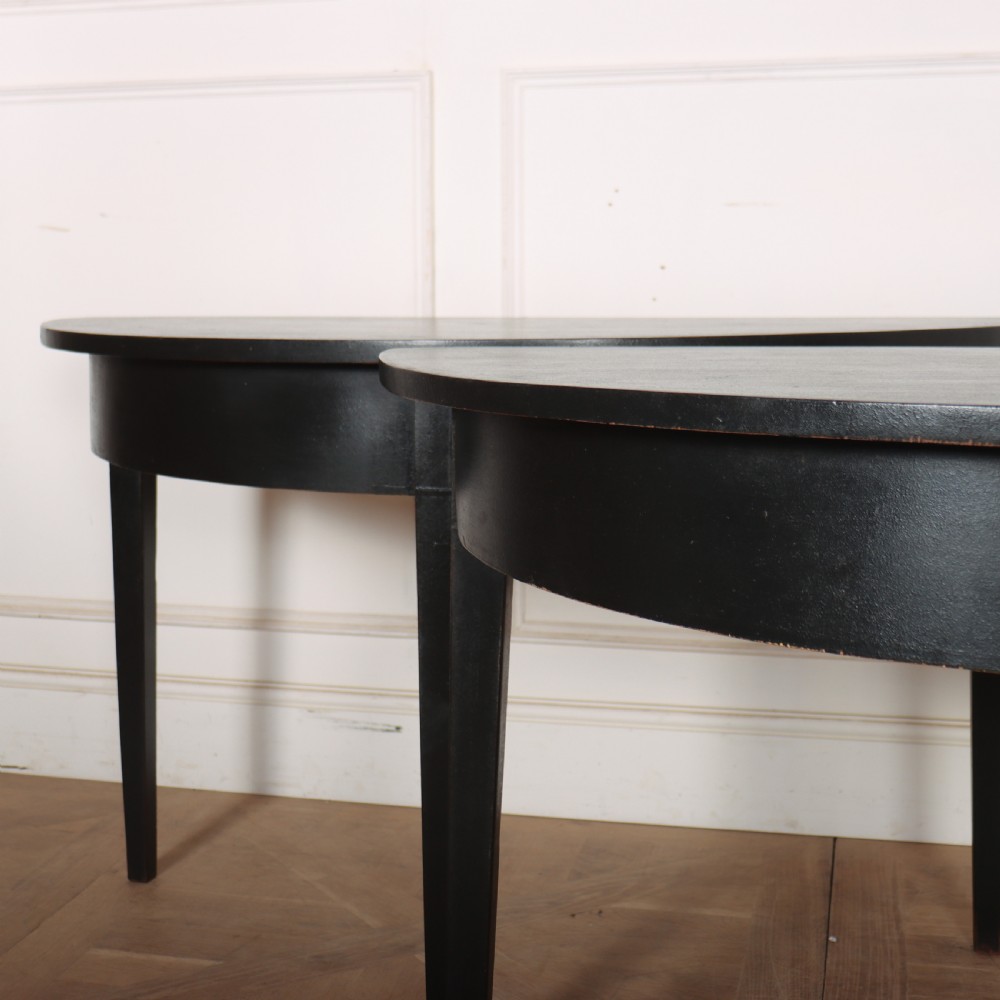 A pair of semi-circular ebonised wooden demi-lune console tables with plain aprons and square tapered legs. View III