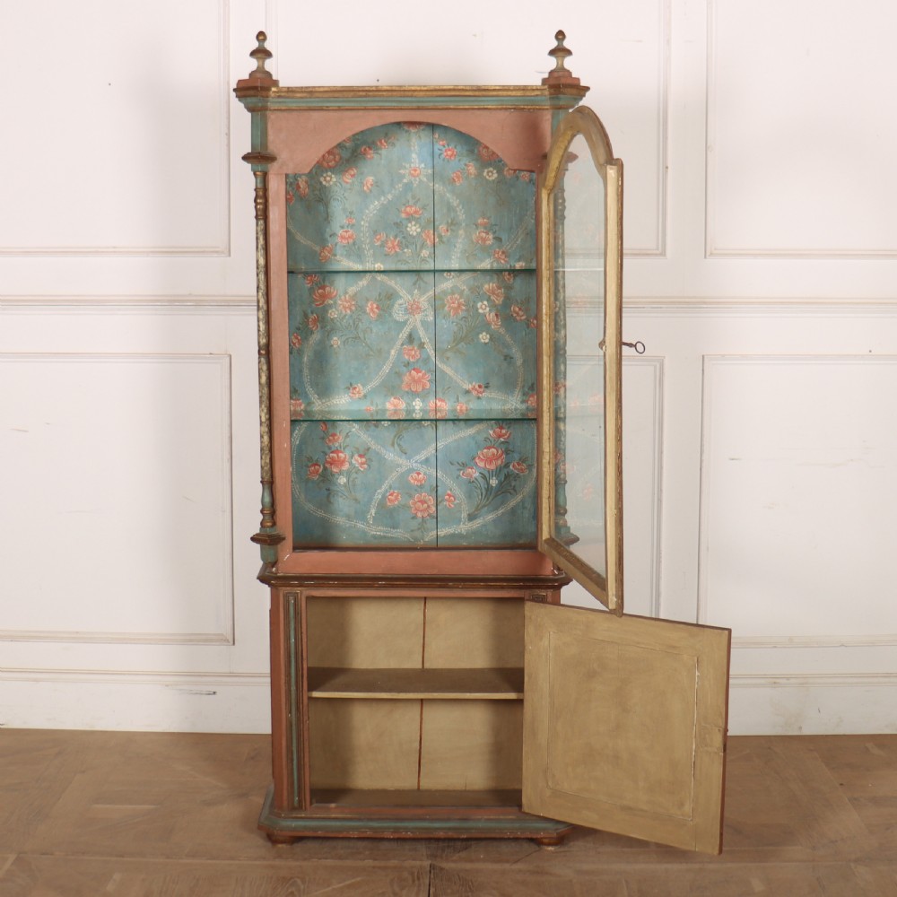 A tall nineteenth-century Italian painted two-tier cabinet featuring a glazed upper display section with a blue floral painted background and a lower solid cupboard door decorated with a painted floral motif. View VII