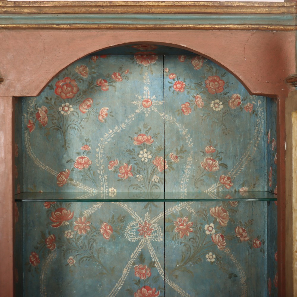 A tall nineteenth-century Italian painted two-tier cabinet featuring a glazed upper display section with a blue floral painted background and a lower solid cupboard door decorated with a painted floral motif. View VIII