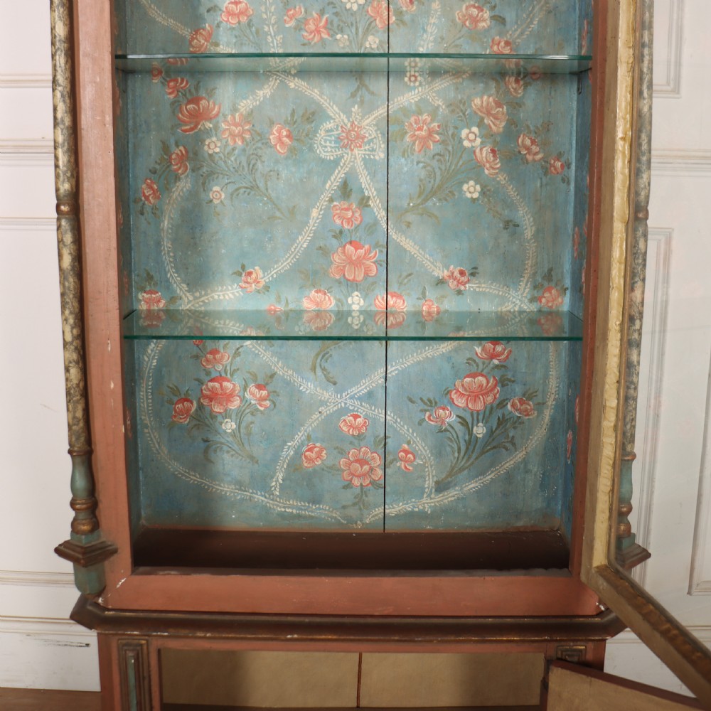 A tall nineteenth-century Italian painted two-tier cabinet featuring a glazed upper display section with a blue floral painted background and a lower solid cupboard door decorated with a painted floral motif. View IX
