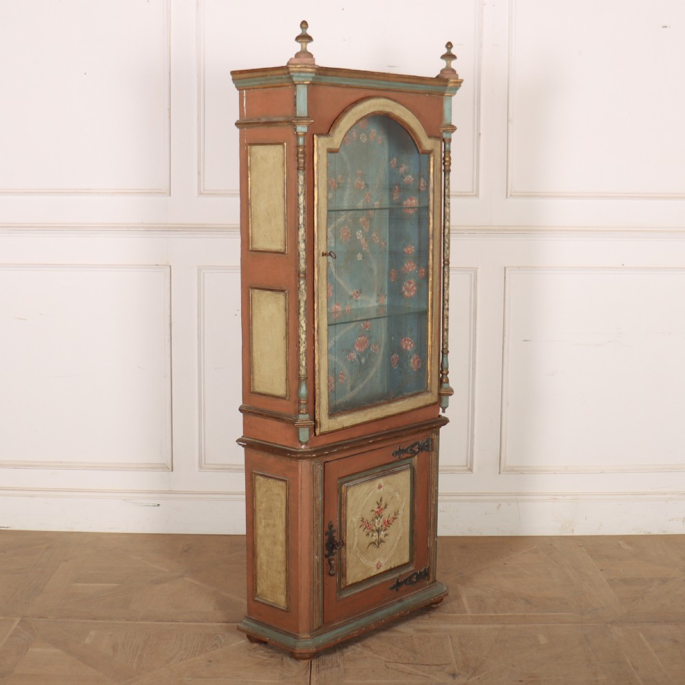A tall nineteenth-century Italian painted two-tier cabinet featuring a glazed upper display section with a blue floral painted background and a lower solid cupboard door decorated with a painted floral motif. View X