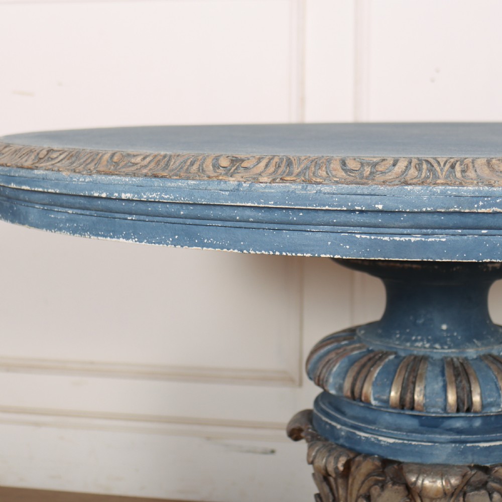 A circular 1920s German centre table featuring a distressed slate blue painted finish, gilt carved acanthus leaf pedestal, and scroll feet. View V